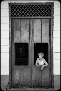 Womand standing at the door of her art shop in Trinidad, Cuba