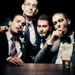 Groomsmen with groom smoking cigar